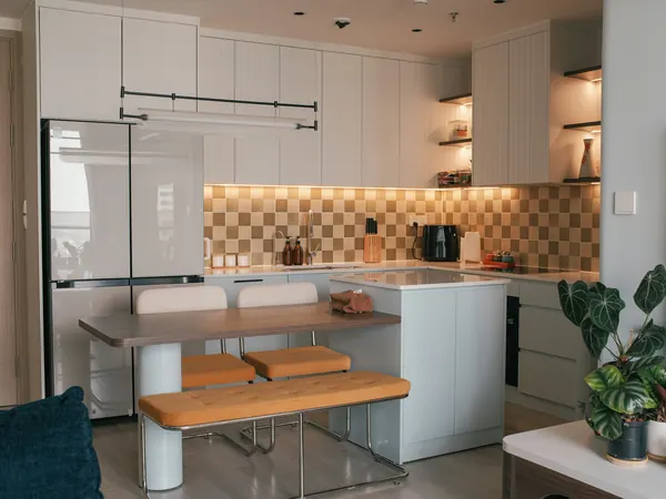 Dapur putih dengan pulau sarapan dan lampu hangat di bawah kabinet